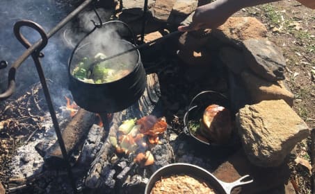 A person cooking food over an open fire.